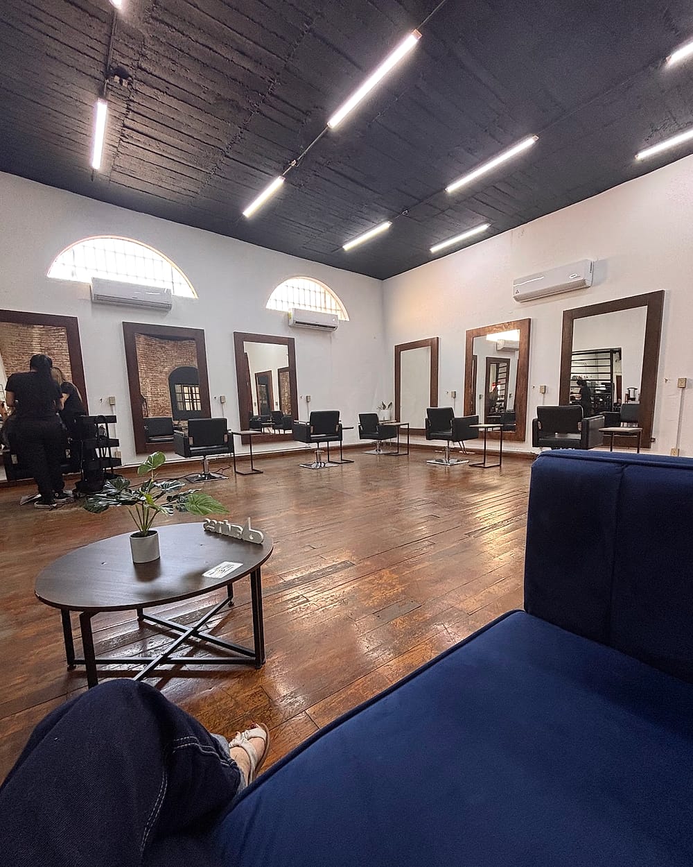 Sala de Bloom23 con sillones de terciopelo azul y espejos en arco